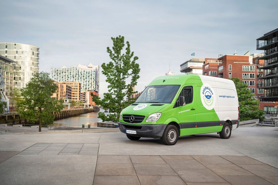 Grün-weißer Transporter von Overnight Express & Logistics in der Hamburger HafenCity, im Hintergrund die Elbphilharmonie